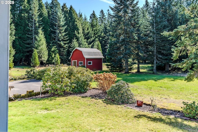 view of yard featuring a garage, a forest view, and an outdoor structure