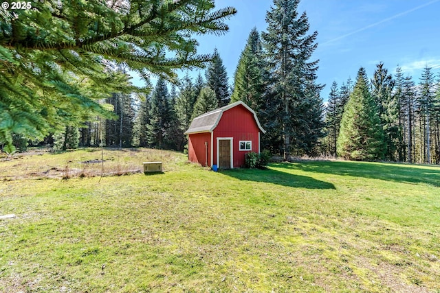 view of yard with an outbuilding, a view of trees, and a barn