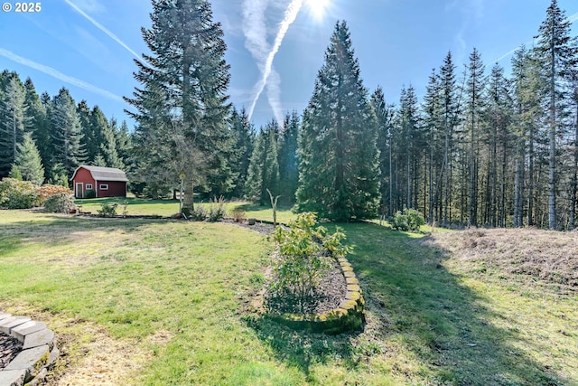 view of yard featuring an outbuilding, a wooded view, and a barn