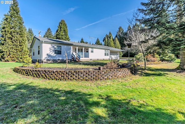 back of property with a yard, crawl space, and an attached garage