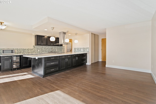 kitchen with kitchen peninsula, island exhaust hood, beverage cooler, hanging light fixtures, and dark wood-type flooring