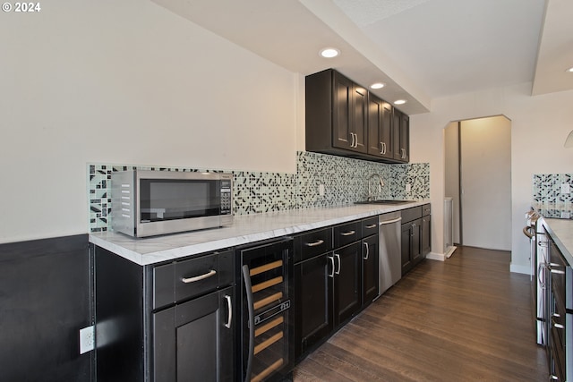 kitchen featuring decorative backsplash, beverage cooler, dark wood-type flooring, sink, and stainless steel appliances