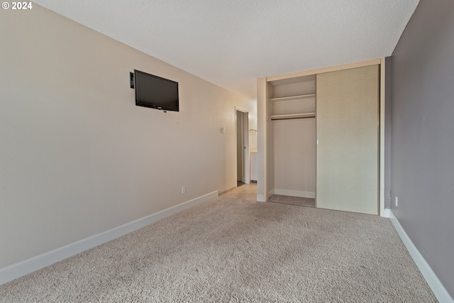 unfurnished bedroom with a closet, a textured ceiling, and light colored carpet