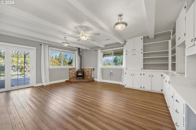 unfurnished living room with hardwood / wood-style flooring, a wood stove, and a healthy amount of sunlight