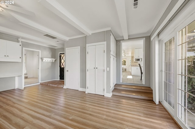 interior space featuring beam ceiling, multiple closets, ensuite bathroom, and light hardwood / wood-style floors