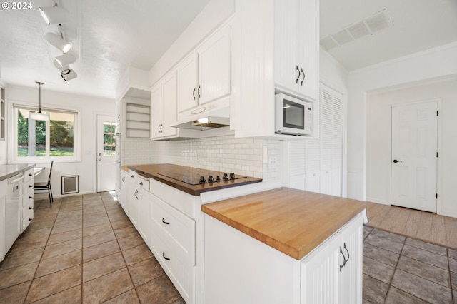 kitchen featuring white cabinetry, decorative light fixtures, and wood counters