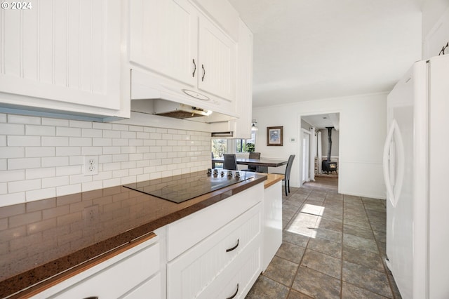 kitchen featuring white cabinets, black electric stovetop, white refrigerator, and tasteful backsplash