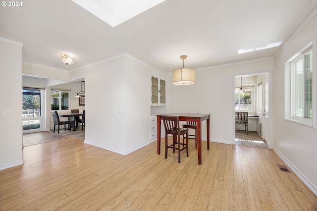 dining space featuring a healthy amount of sunlight, light hardwood / wood-style floors, and ornamental molding