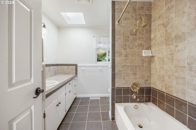 bathroom featuring tile patterned floors, a skylight, vanity, and tiled shower / bath combo