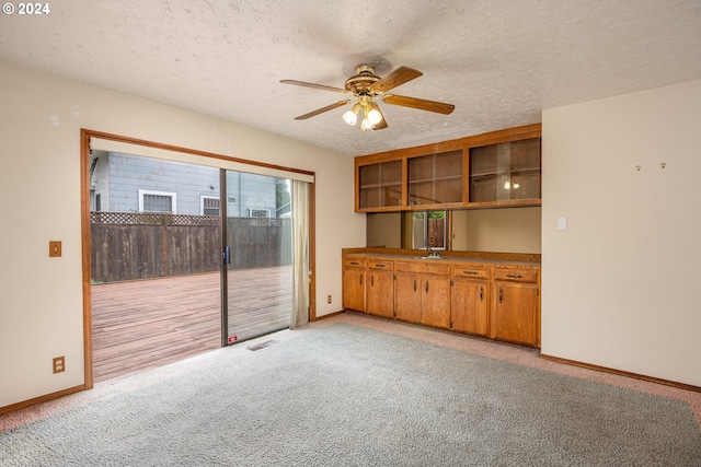 carpeted empty room with ceiling fan, a textured ceiling, and sink