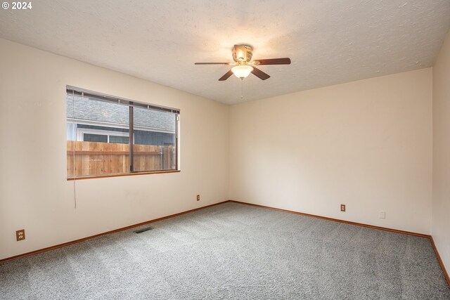 empty room featuring ceiling fan, light carpet, and a textured ceiling