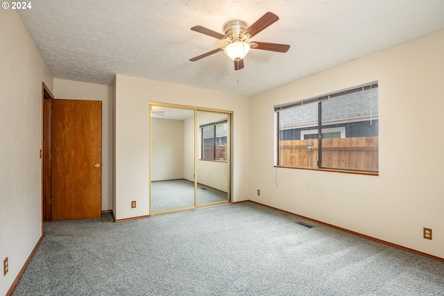 unfurnished bedroom featuring ceiling fan, carpet flooring, a textured ceiling, and a closet