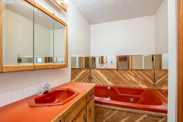 bathroom featuring a textured ceiling, vanity, and a tub to relax in