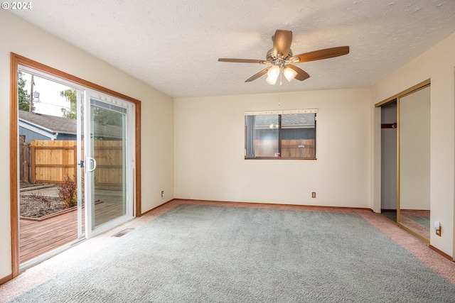 unfurnished bedroom with carpet floors, access to exterior, a textured ceiling, and ceiling fan