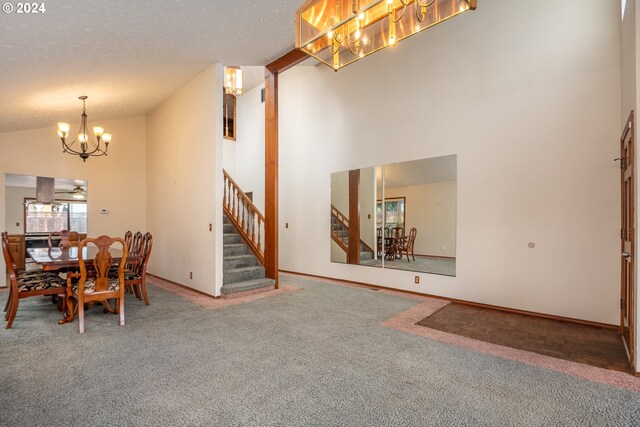 dining space with a textured ceiling, carpet flooring, high vaulted ceiling, and ceiling fan with notable chandelier