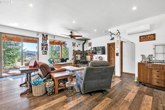 living room with a textured ceiling, dark hardwood / wood-style flooring, a wood stove, ceiling fan, and a wall mounted air conditioner