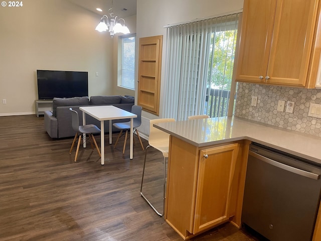 kitchen with hanging light fixtures, dark hardwood / wood-style flooring, stainless steel dishwasher, kitchen peninsula, and a chandelier