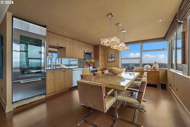 kitchen with appliances with stainless steel finishes, light brown cabinets, hanging light fixtures, and sink