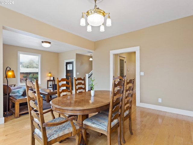 dining room featuring stairway, baseboards, light wood-type flooring, and a chandelier