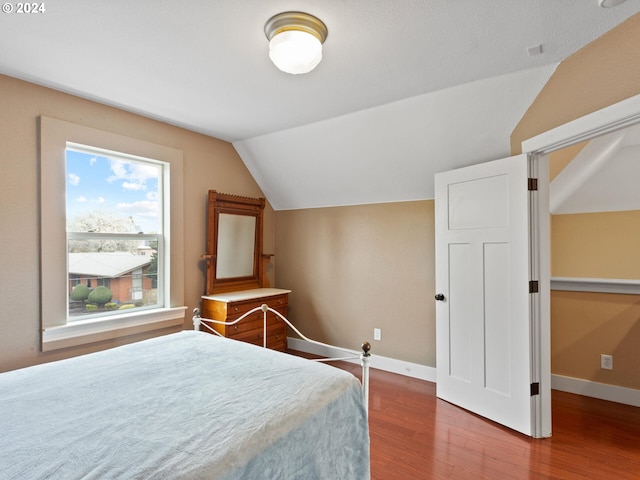 bedroom featuring lofted ceiling, wood finished floors, and baseboards