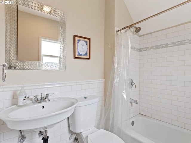 bathroom with a sink, wainscoting, tile walls, toilet, and shower / tub combo with curtain