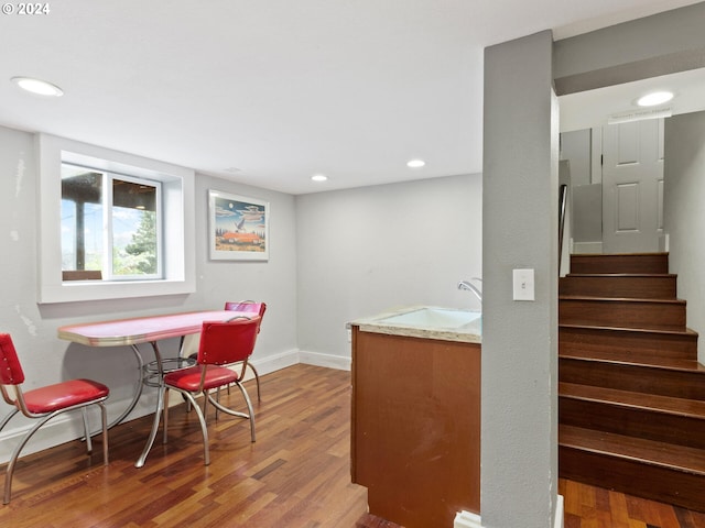 interior space featuring baseboards, stairs, recessed lighting, wood finished floors, and a sink