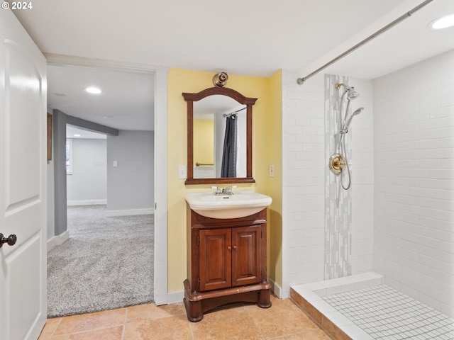 bathroom featuring a tile shower, vanity, and baseboards