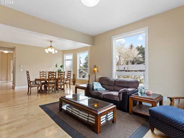 living area featuring an inviting chandelier, baseboards, and light wood finished floors