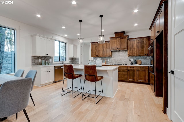 kitchen featuring white cabinetry, decorative light fixtures, a center island, and dishwasher