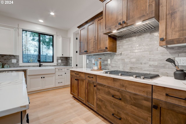 kitchen with premium range hood, sink, white cabinets, backsplash, and stainless steel appliances