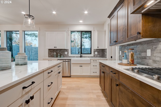 kitchen with stainless steel appliances, white cabinetry, sink, and wall chimney range hood