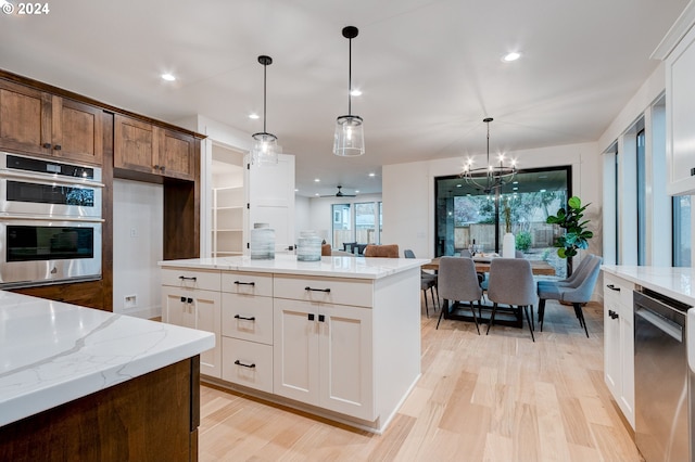 kitchen featuring light stone countertops, appliances with stainless steel finishes, pendant lighting, and white cabinets