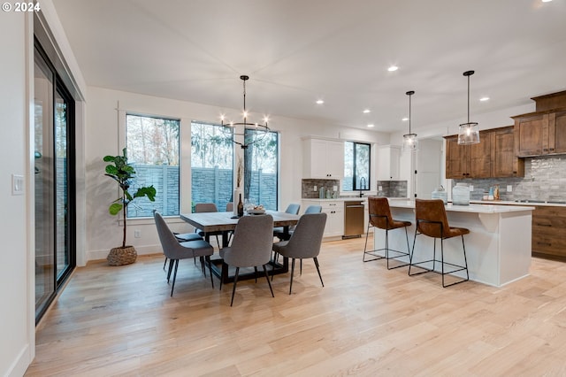 dining area with sink, a chandelier, and light wood-type flooring