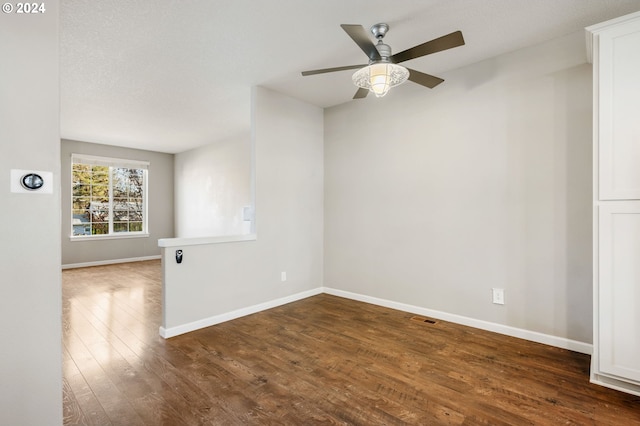 unfurnished room with ceiling fan, dark hardwood / wood-style flooring, and a textured ceiling