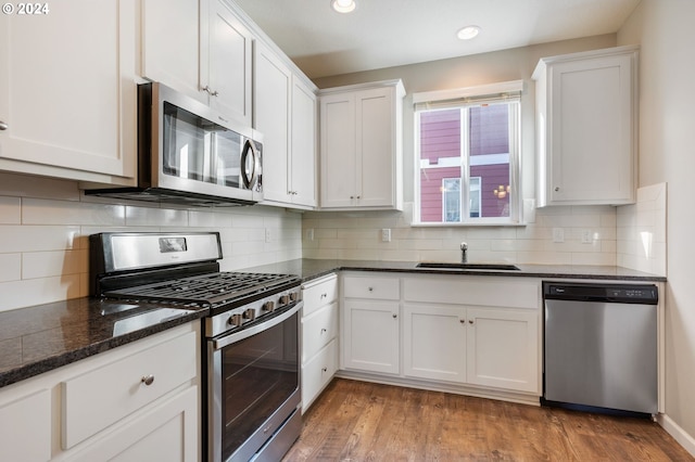 kitchen featuring tasteful backsplash, stainless steel appliances, sink, white cabinets, and hardwood / wood-style floors