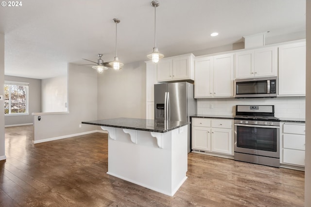 kitchen featuring white cabinets, appliances with stainless steel finishes, backsplash, and hardwood / wood-style flooring