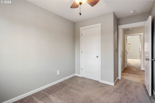 unfurnished bedroom featuring light carpet and ceiling fan