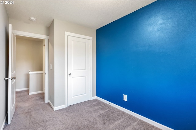 unfurnished bedroom with light colored carpet and a textured ceiling