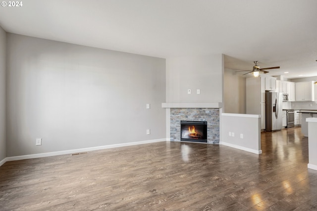 unfurnished living room with ceiling fan, a fireplace, and dark hardwood / wood-style floors