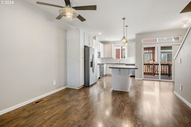 kitchen with a kitchen breakfast bar, appliances with stainless steel finishes, a kitchen island, dark hardwood / wood-style flooring, and white cabinetry