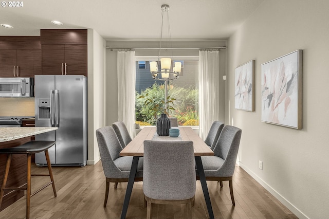 dining area with light hardwood / wood-style flooring and an inviting chandelier