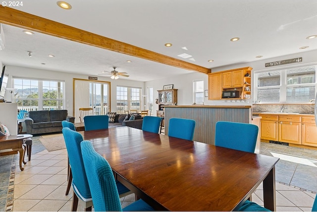 tiled dining space featuring ceiling fan, beamed ceiling, and sink