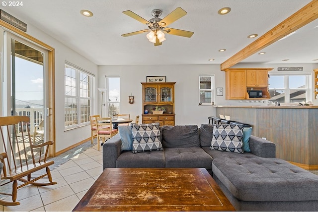 living room with ceiling fan, plenty of natural light, light tile patterned floors, and a textured ceiling