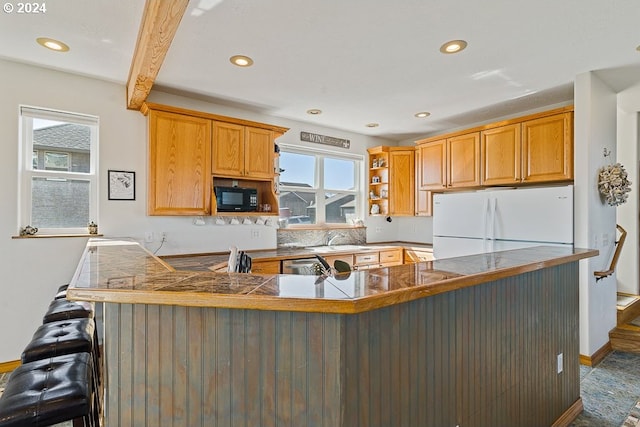 kitchen with beamed ceiling, sink, kitchen peninsula, a kitchen breakfast bar, and white fridge