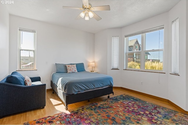 bedroom with ceiling fan, a textured ceiling, and wood-type flooring