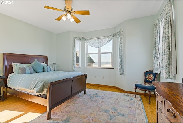 bedroom featuring light wood finished floors, baseboards, and a ceiling fan