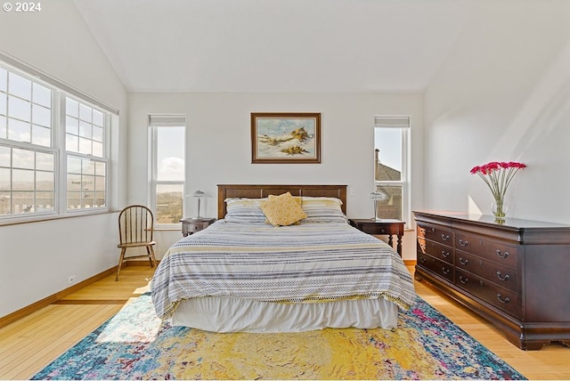 bedroom with light wood-style flooring, multiple windows, and lofted ceiling
