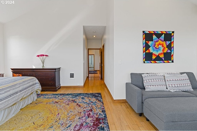 bedroom with a high ceiling, baseboards, visible vents, and hardwood / wood-style flooring