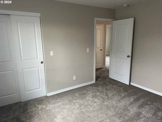 unfurnished bedroom with a closet and dark colored carpet