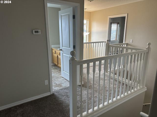 hallway with light colored carpet and a textured ceiling